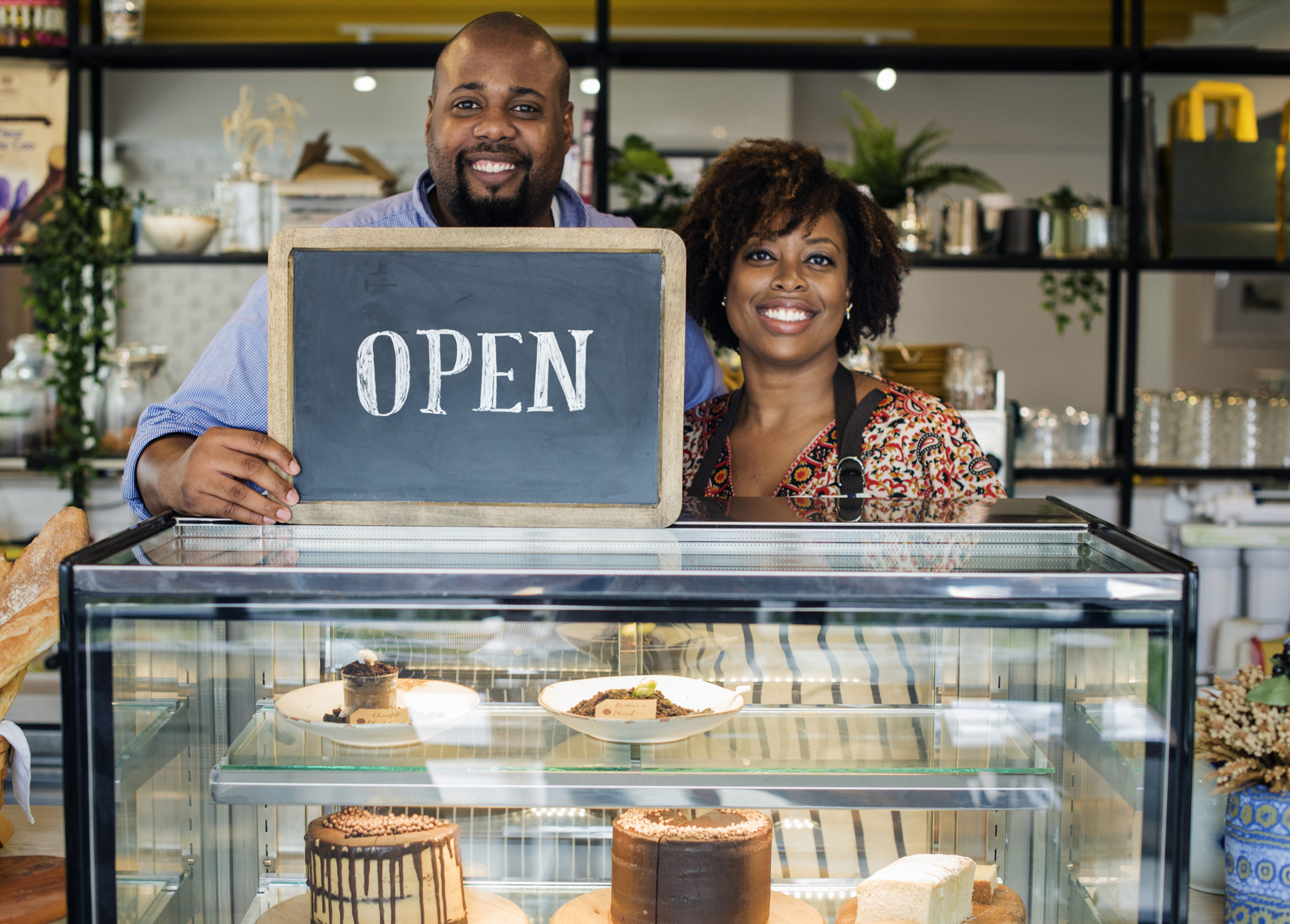 Cake cafe owners with open sign